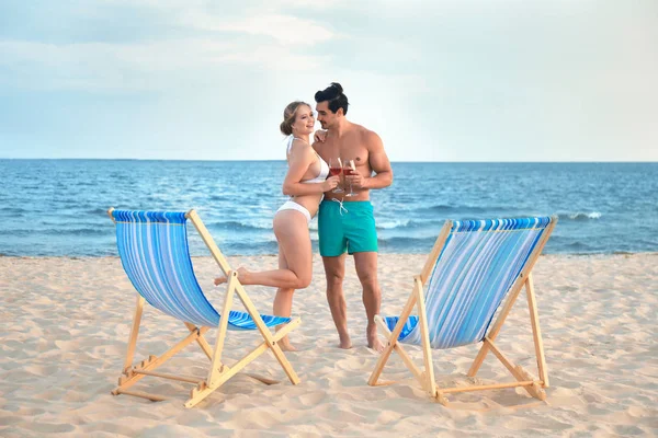 Feliz jovem casal perto de espreguiçadeiras na praia do mar — Fotografia de Stock