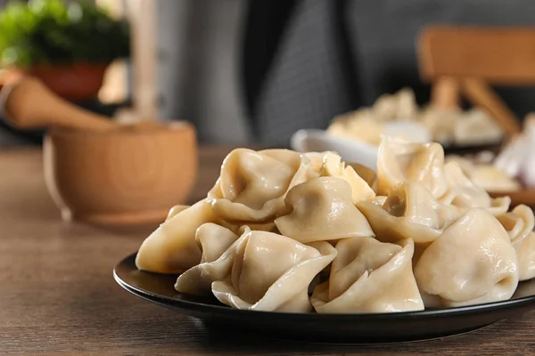 Läckra dumplings med smör på träbord mot suddig bakgrund — Stockfoto