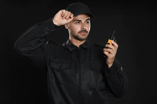 Protetor de segurança masculino em uniforme usando transmissor de rádio portátil em fundo escuro — Fotografia de Stock