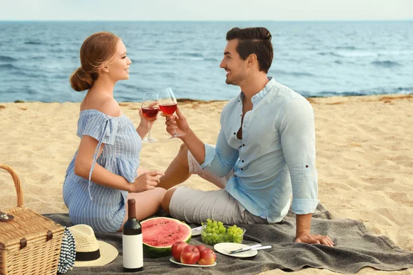 Hermosa pareja joven teniendo picnic en la playa del mar — Foto de Stock