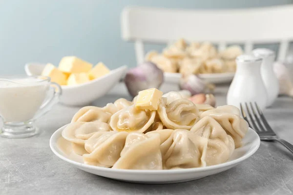 Läckra dumplings med smör på ljusgrå bord mot suddig bakgrund — Stockfoto