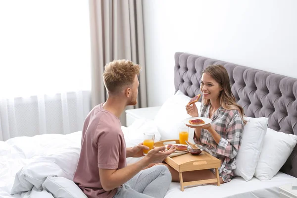 Feliz pareja joven desayunando romántico en la cama en casa — Foto de Stock
