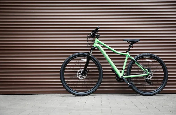 Nueva bicicleta de color moderno cerca de la pared marrón al aire libre —  Fotos de Stock