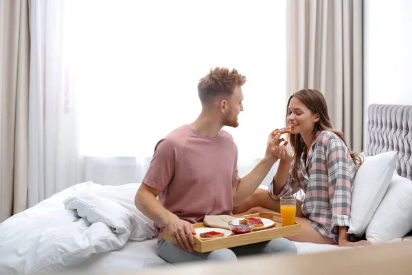 Feliz pareja joven desayunando romántico en la cama en casa — Foto de Stock