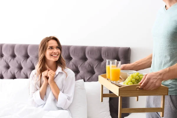 Joven trayendo desayuno romántico a su novia en la cama en casa — Foto de Stock