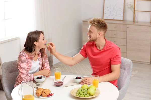 Счастливая молодая пара завтракает за столом в номере — стоковое фото