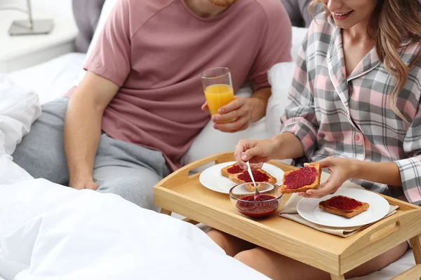 Feliz pareja joven desayunando románticamente en la cama en casa, primer plano — Foto de Stock