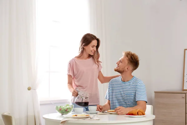Feliz pareja joven desayunando en la mesa en la habitación —  Fotos de Stock