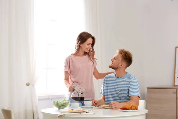 Feliz pareja joven desayunando en la mesa en la habitación — Foto de Stock