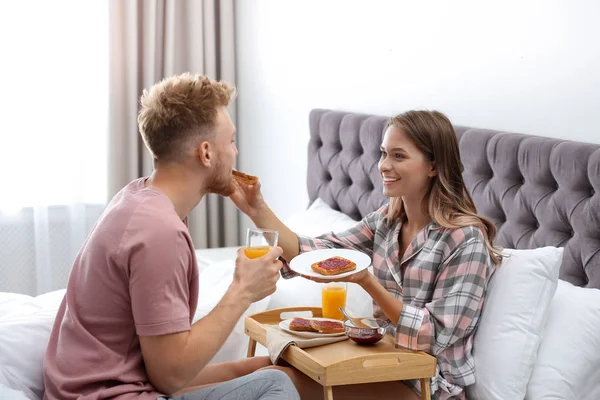 Feliz pareja joven desayunando romántico en la cama en casa — Foto de Stock