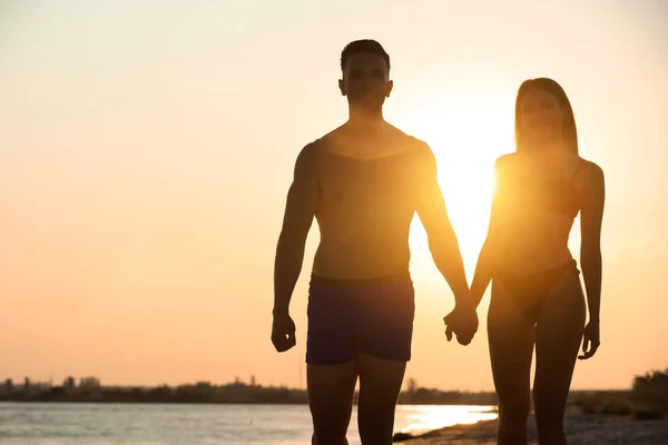 Jovem de biquíni passando tempo com o namorado na praia ao pôr do sol. Casal encantador — Fotografia de Stock