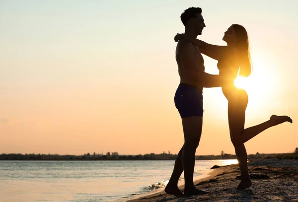 Junge Frau im Bikini verbringt Zeit mit ihrem Freund am Strand bei Sonnenuntergang. Liebes Paar — Stockfoto