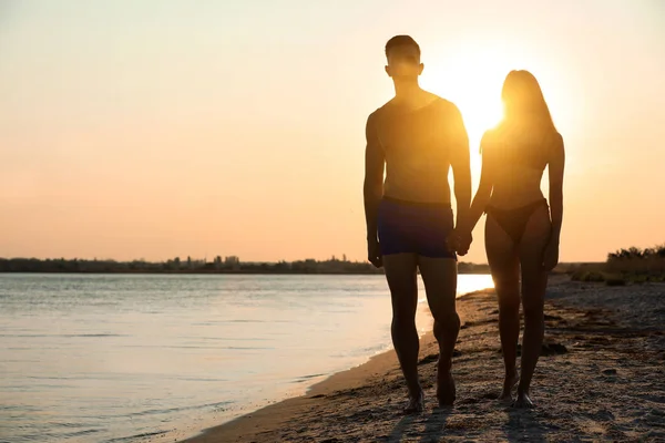 Jovem de biquíni passando tempo com o namorado na praia ao pôr do sol. Casal encantador — Fotografia de Stock