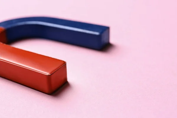 Ímã de ferradura vermelho e azul no fundo rosa, close-up — Fotografia de Stock