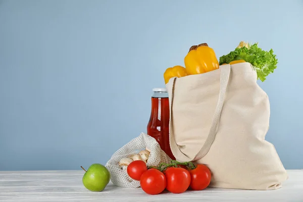 Bolsa de compras con verduras frescas y otros productos sobre mesa de madera blanca sobre fondo azul claro, espacio para texto —  Fotos de Stock