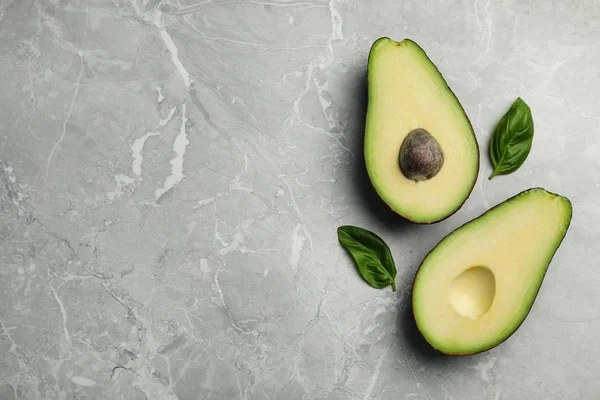 Halvor av läcker mogen avokado på grått marmorbord, platt låg. Utrymme för text — Stockfoto