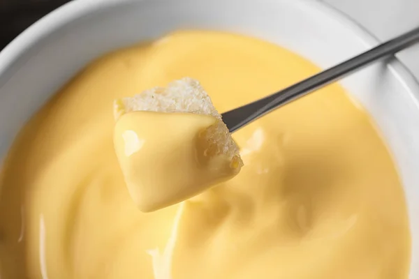 Dipping bread into tasty cheese fondue, closeup — Stock Photo, Image