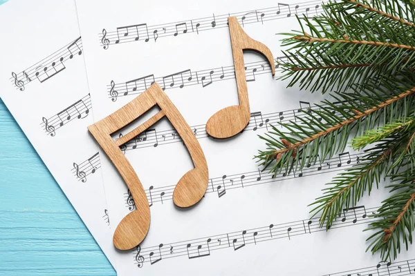 Rama de árbol de Navidad, notas y hojas de música sobre una mesa de madera azul, plano —  Fotos de Stock