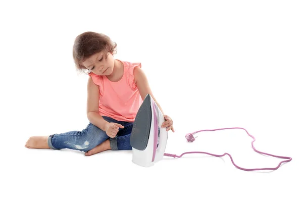 Little girl playing with iron on white background. Danger at home — Stock Photo, Image