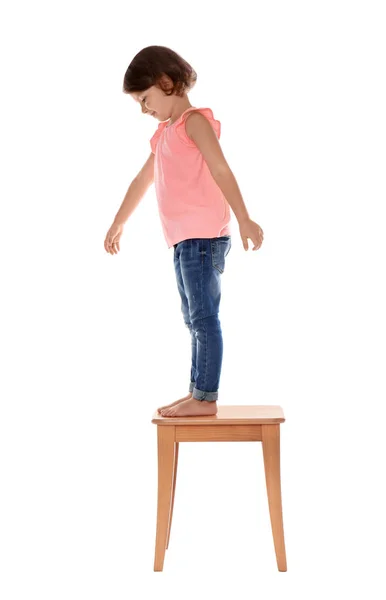 Little girl on stool against white background. Danger at home — Stock Photo, Image