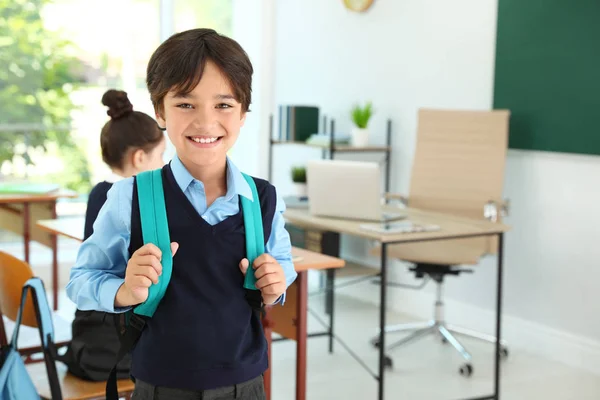 Chłopiec nosi mundur szkolny z plecakiem w klasie — Zdjęcie stockowe