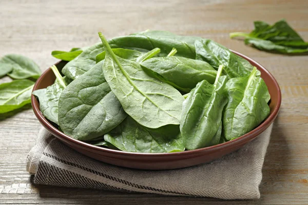 Kom met verse groene gezonde spinazie op houten tafel — Stockfoto