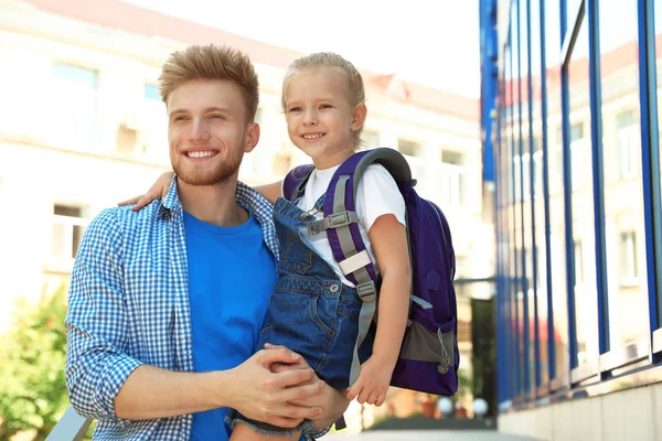 Genç baba okul çantası ile açık havada küçük çocuğu tutarak — Stok fotoğraf