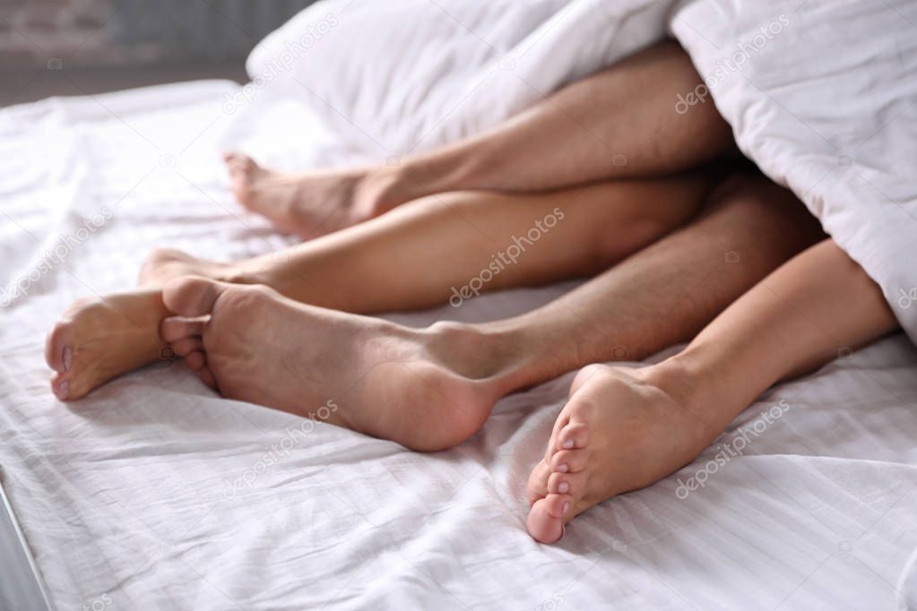 Passionate young couple having sex on bed, closeup of legs