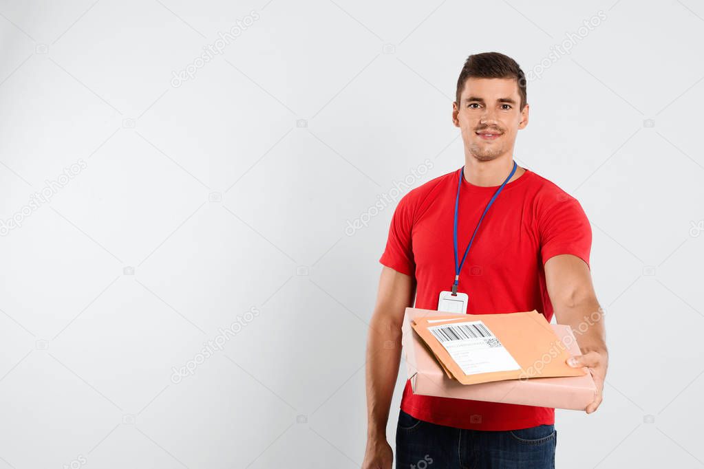Happy young courier with parcel and envelopes on white background. Space for text