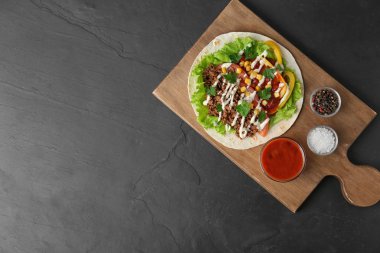 Koyu masaüzerinde et ve sebze ile lezzetli tortilla, üst görünümü. Metin için alan