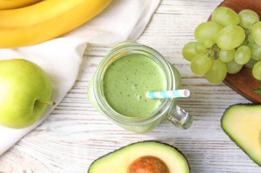 Beyaz ahşap masa üzerinde lezzetli avokado smoothie ile Düz yatıyordu kompozisyon