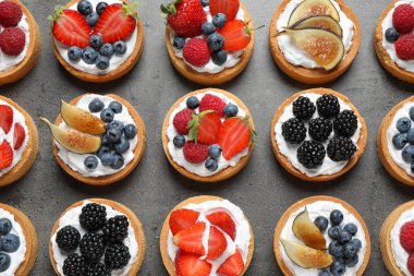 Gri masada farklı berry tart, düz yatıyordu. Lezzetli hamur işleri