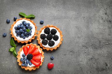 Gri masada farklı meyveleri ile Tarts, metin için alan ile üst görünüm. Lezzetli hamur işleri