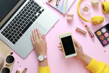 Açık pembe arka plan üzerinde dizüstü bilgisayar ve akıllı telefon ile Genç güzellik blogger, üst görünüm