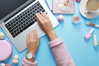 Genç güzellik blogger açık mavi arka plan üzerinde dizüstü bilgisayar ile çalışan, üst görünümü