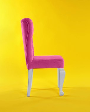 Sarı arka plan üzerinde şık pembe sandalye. İç tasarım unsuru