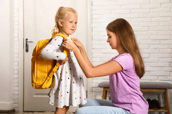 Jovem mãe ajudando seu filho a colocar no saco da escola em casa — Fotografia de Stock