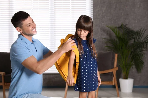 Lycklig far hjälpa sitt lilla barn att sätta på skolväska hemma — Stockfoto
