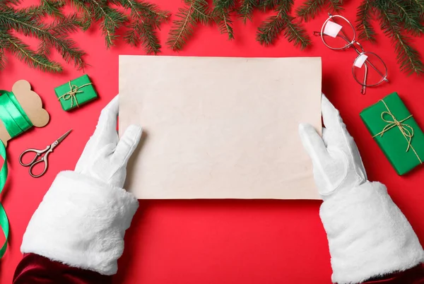 Santa Claus sosteniendo papel vacío sobre fondo rojo, vista superior. Espacio para texto — Foto de Stock