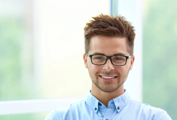 Porträt eines gutaussehenden jungen Mannes mit Brille am Fenster — Stockfoto