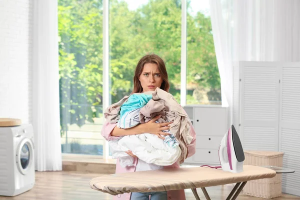 Moe meisje houden ongevouwen Wasserij in de buurt van strijkplank thuis — Stockfoto