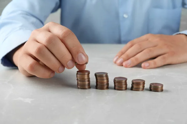 Hombre apilando monedas en la mesa de piedra gris, vista de cerca — Foto de Stock