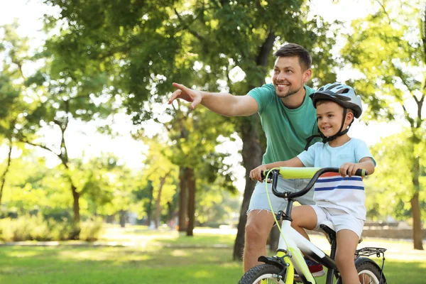 Szczęśliwy ojciec nauczanie jego syn do jazda rower w Park — Zdjęcie stockowe