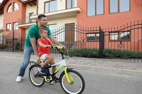 Père heureux enseignant à son fils à faire du vélo dans la rue — Photo