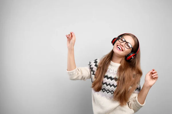 Νεαρή γυναίκα ακούγοντας μουσική με ακουστικά σε γκρίζο φόντο, Χώρος για κείμενο — Φωτογραφία Αρχείου