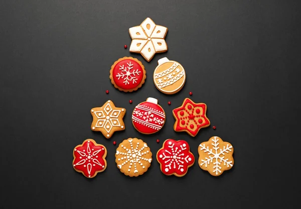 Forma de árvore de Natal feito de biscoitos caseiros saborosos no fundo preto, flat lay — Fotografia de Stock