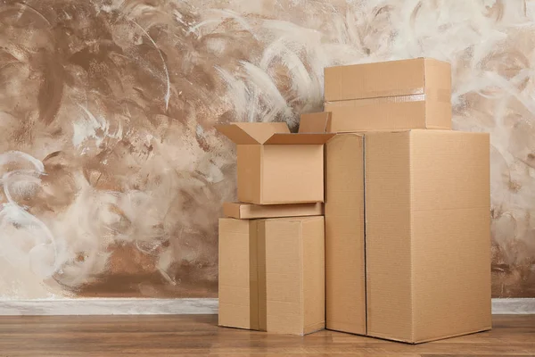 Pile of cardboard boxes near brown wall indoors. Space for text — Stock Photo, Image