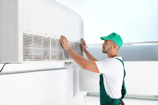 Professional technician maintaining modern air conditioner indoors — Stock Photo, Image