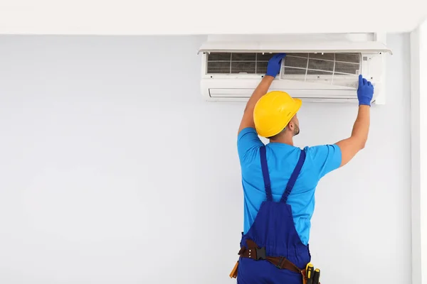 Técnico profissional mantendo ar condicionado moderno dentro de casa. Espaço para texto — Fotografia de Stock