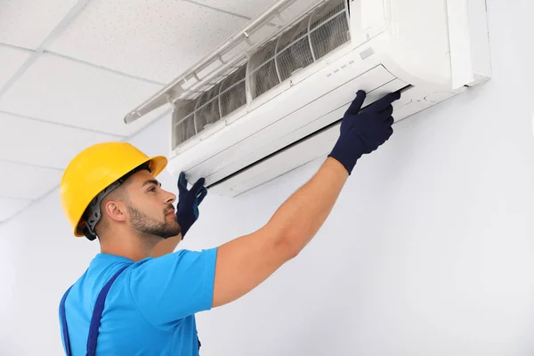 Professional technician maintaining modern air conditioner indoors — Stock Photo, Image